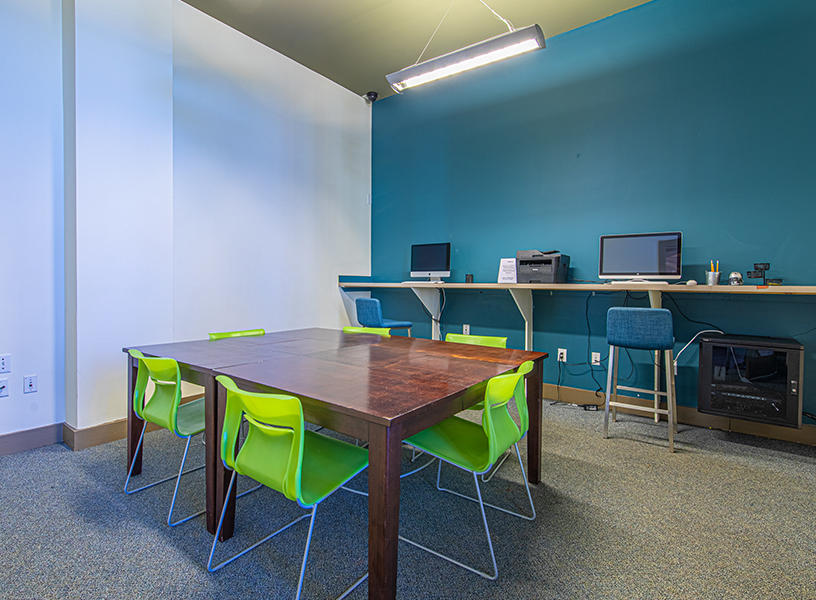 Study room with table, counter, plenty of seating, computers and printers.