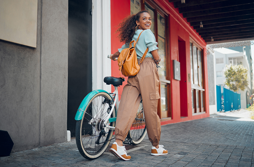 A young woman walking with her bike, looking back at the camera